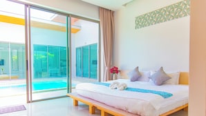 A modern bedroom with a large bed, a bench, a vase with flowers, and a view of a swimming pool through glass doors. - Alhambra Pool Villas & Pool Access Rooms (Rawai)