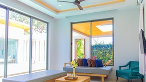 A modern living room with a sofa, a wooden coffee table, and a teal armchair. - Alhambra Pool Villas & Pool Access Rooms (Rawai)