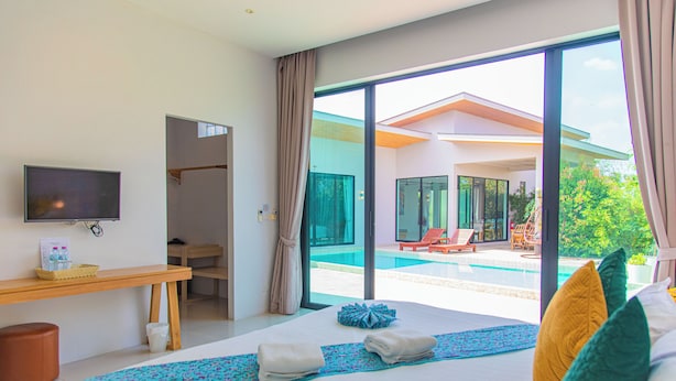 A hotel room with a bed, a TV, a desk, and a view of a swimming pool. - Alhambra Pool Villas & Pool Access Rooms (Rawai)