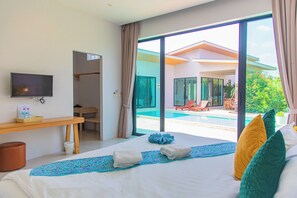 A hotel room with a bed, a TV, a desk, and a view of a swimming pool. - Alhambra Pool Villas & Pool Access Rooms (Rawai)