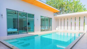 A modern pool area with glass doors leading to a room, a clear pool, and a wooden ceiling. - Alhambra Pool Villas & Pool Access Rooms (Rawai)