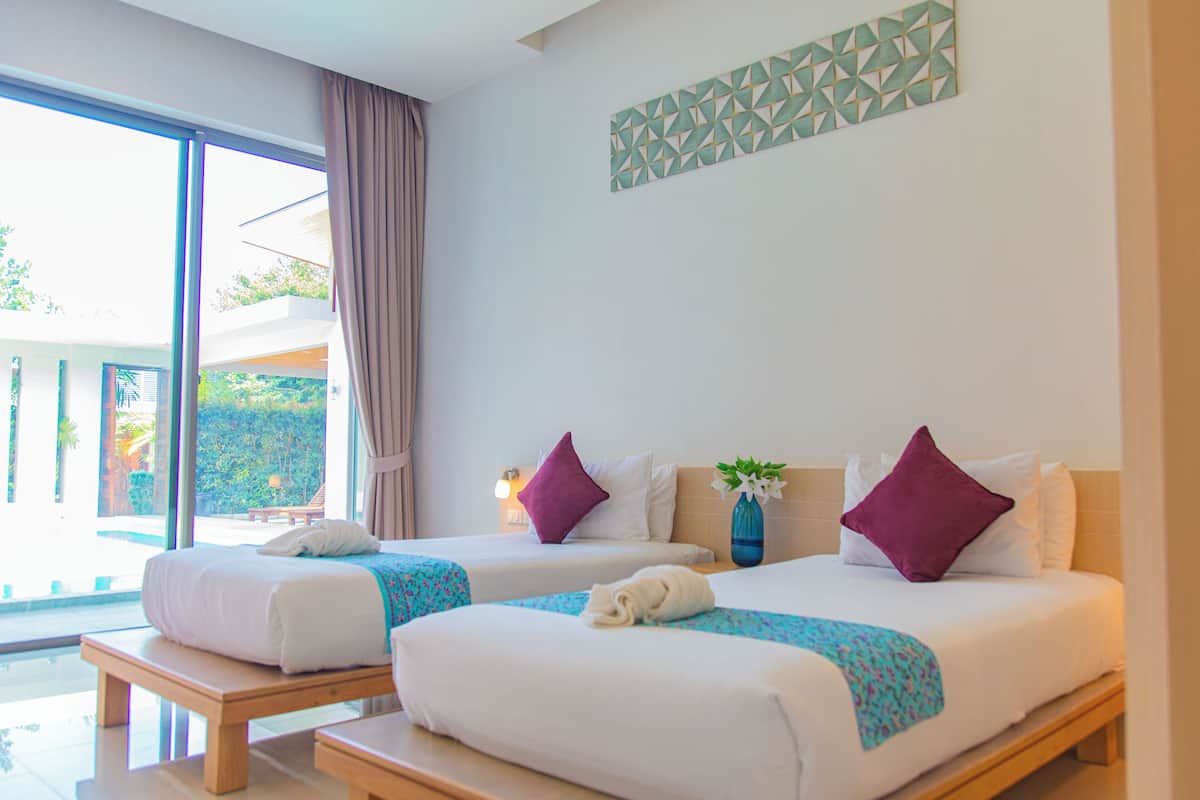 A hotel room with two beds, a large window, and a view of the outdoors.