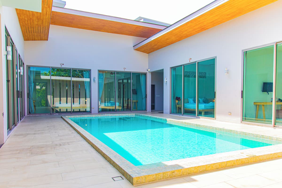 A modern house with a swimming pool, sliding glass doors, and a wooden ceiling.