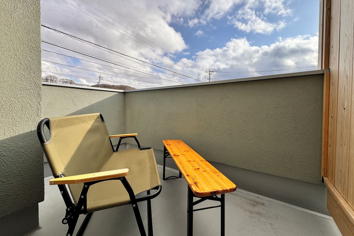 Un balcone con un tavolo di legno e due sedie.