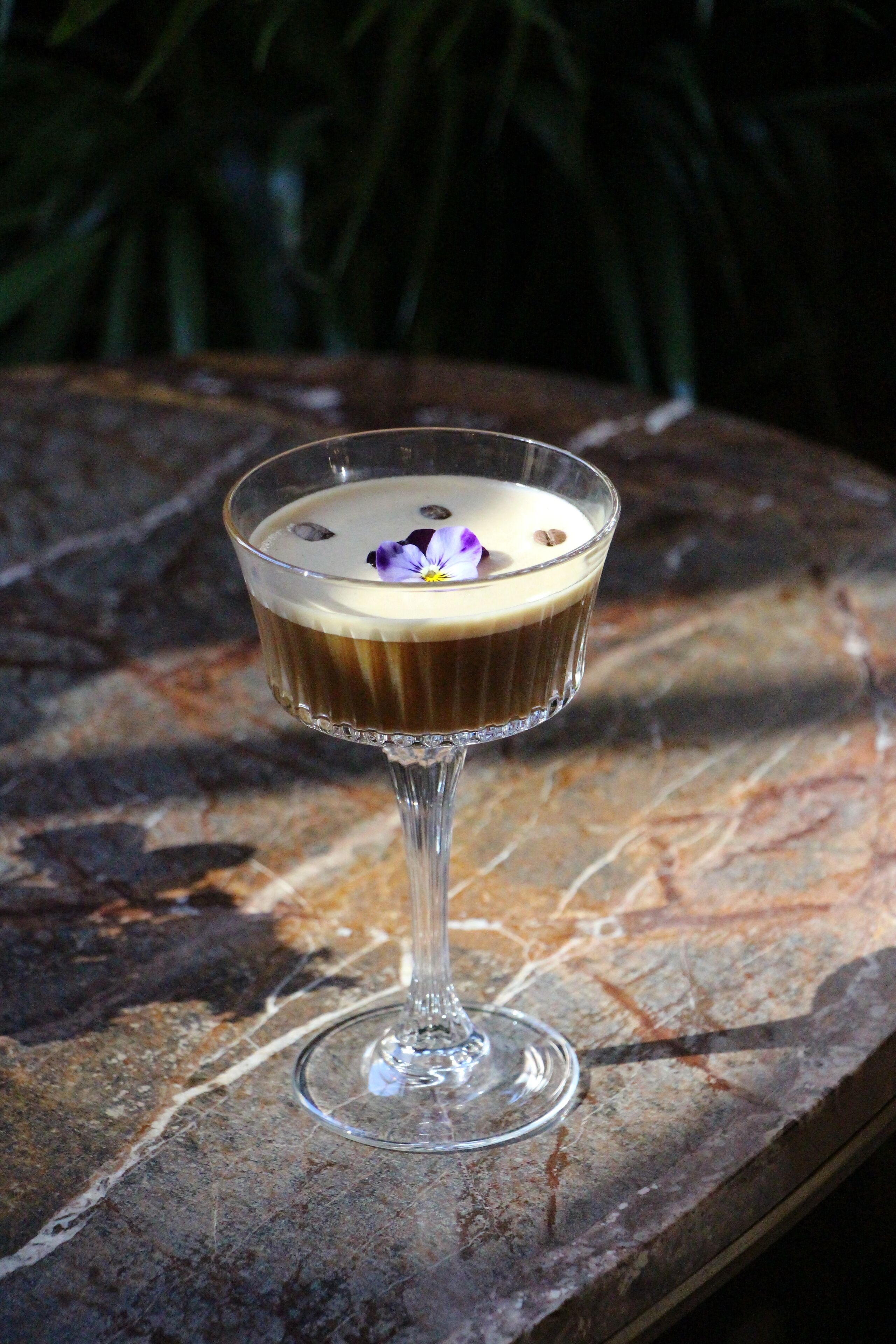 Postre transparente en un recipiente de vidrio sobre una superficie de piedra, con un fondo verde desenfocado.