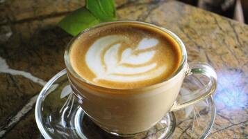 A cup of coffee with latte art on a clear glass saucer on a textured surface.