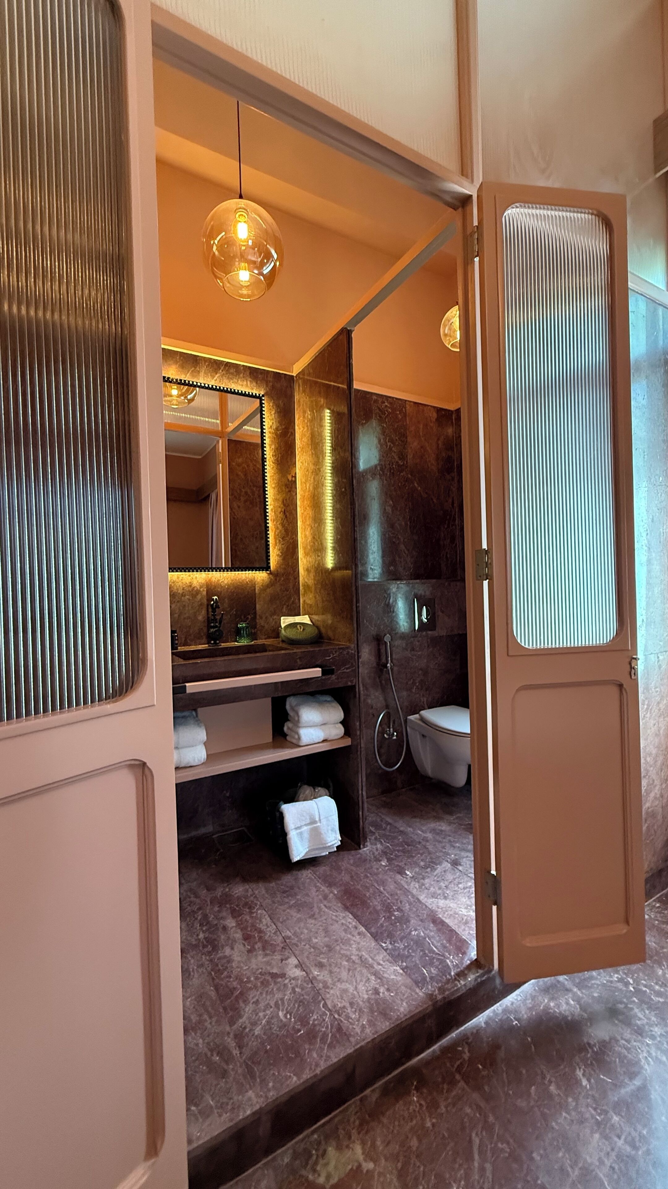 Un baño moderno con tocador, espejo, toallero y retrete.