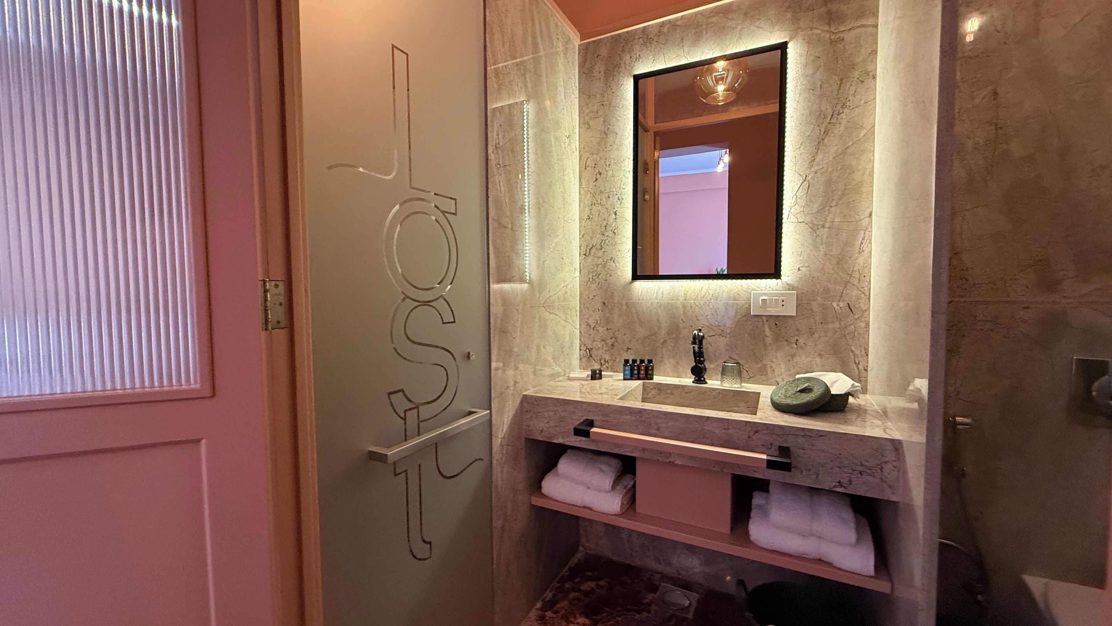 A bathroom with a marble sink, a mirror, and a towel rack.