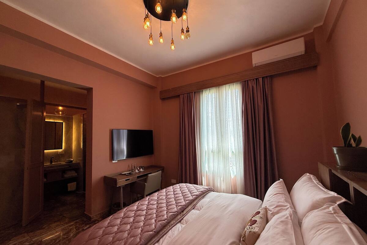Une chambre d’hôtel avec un lit, un bureau, une télévision et une salle de bain, le tout visible à travers une porte ouverte.