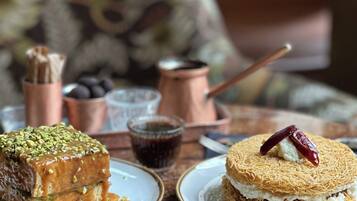 A table with two plates of dessert, a cup of coffee, and a fork.