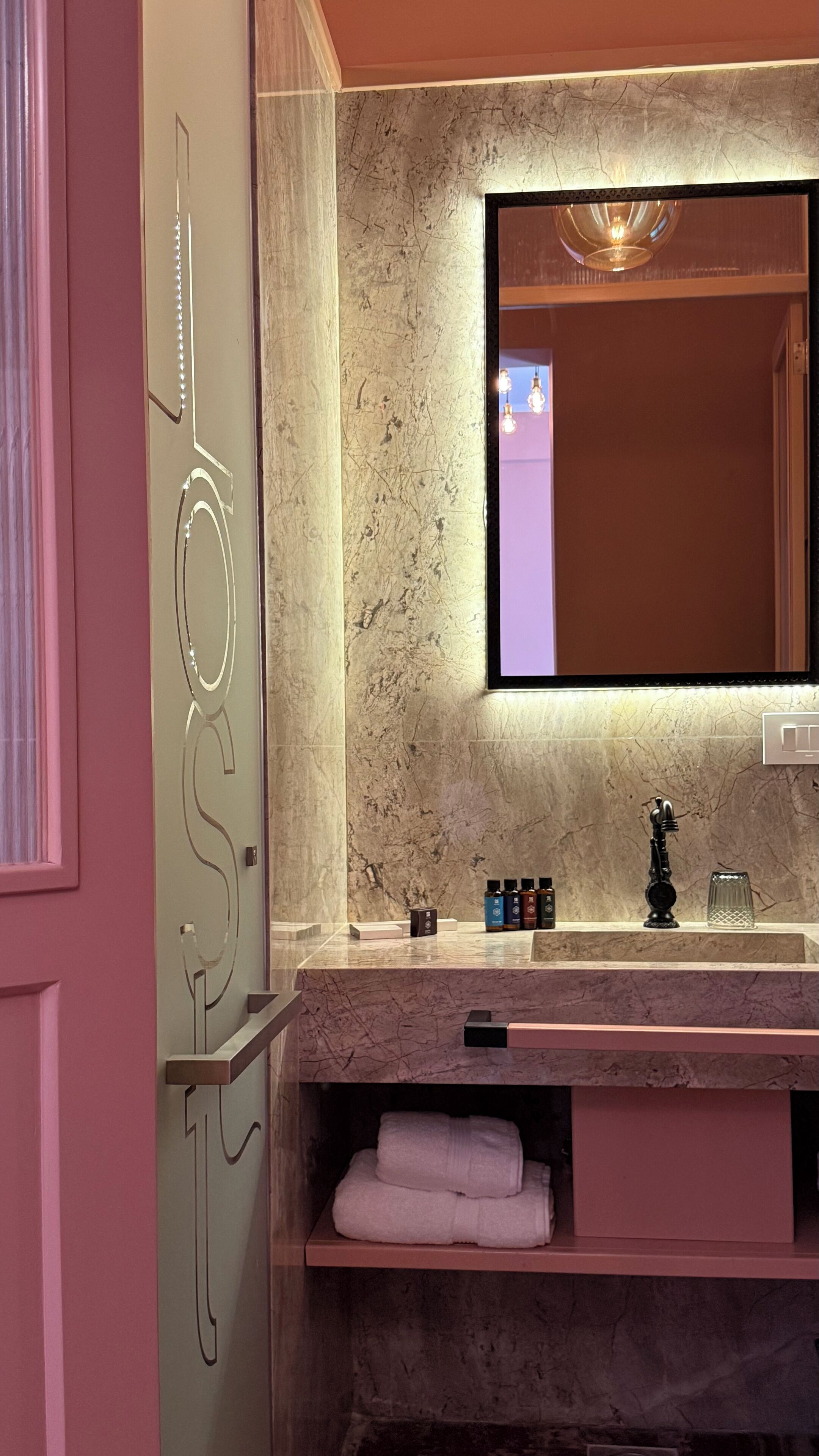 A bathroom with a marble countertop, a large mirror, and a towel rack.