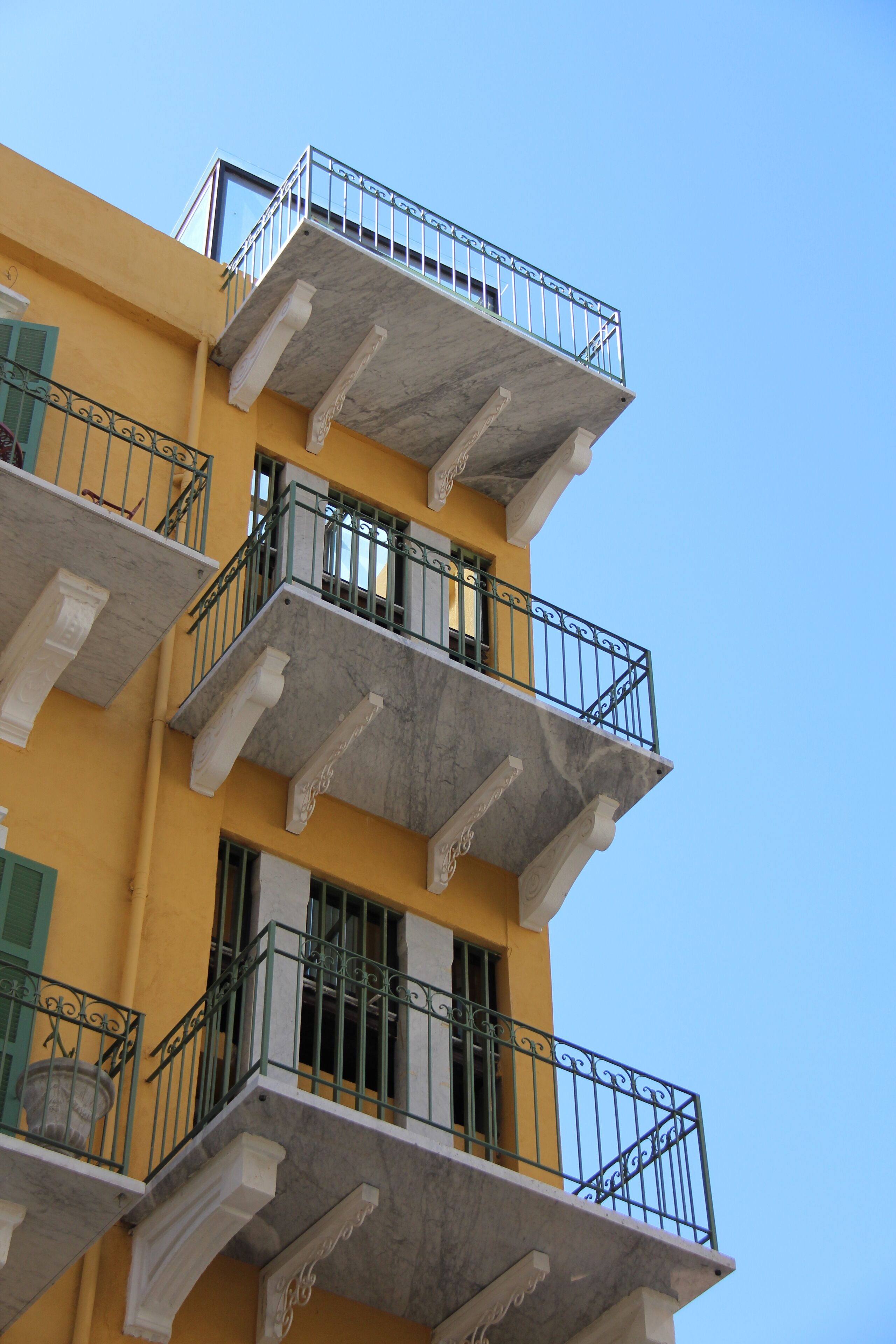 A multi-story building with balconies, each with a metal railing.