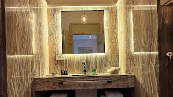 Un baño con tocador de mármol, un espejo y un perchero para toallas.