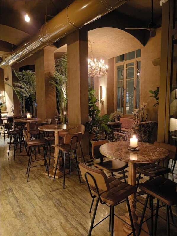 Un restaurante con mesas y sillas redondas, una araña y plantas en macetas.