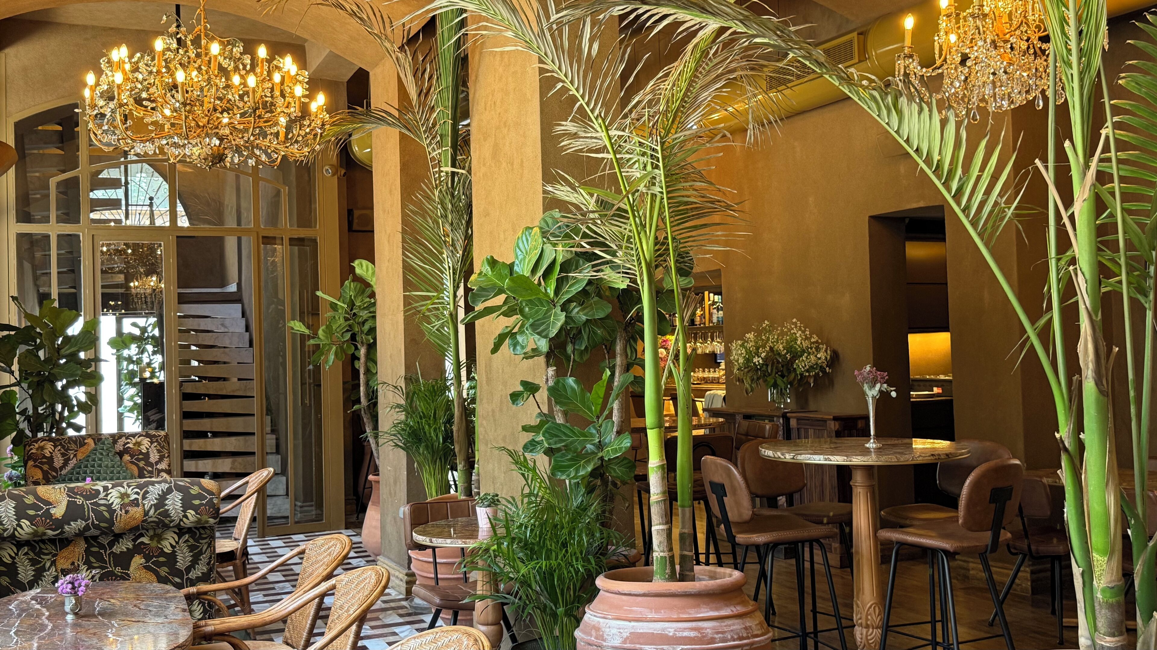 Un vestíbulo espacioso con techos altos, candelabros ornamentales y diversas opciones de asientos, incluyendo sofás y sillones.