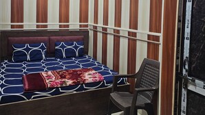 A bedroom with a bed, a chair, a ceiling fan, and wooden paneling on the walls. - Ramlala Paying Guest House (Ayodhya)