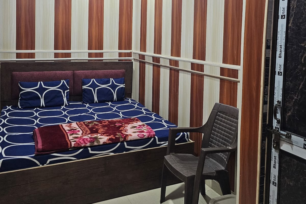 A bedroom with a bed, a chair, a ceiling fan, and wooden paneling on the walls.