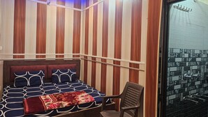 A bedroom with a bed, a chair, and a view of a tiled area. - Ramlala Paying Guest House (Ayodhya)