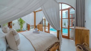 A bedroom with a canopy bed, a view of a swimming pool, and a wooden cabinet.