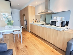 A modern kitchen with a central island, built-in oven, microwave, and coffee machine.