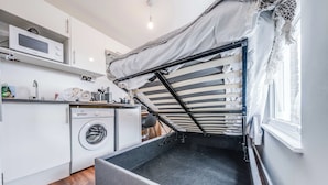 A compact room with a bed, a washing machine, and a microwave. - Camberwell Studios, 10 mins to Station (London)
