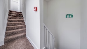 A staircase with carpeted steps and a white railing, a fire exit sign on the wall, and a red fire alarm box. - Camberwell Studios, 10 mins to Station (London)