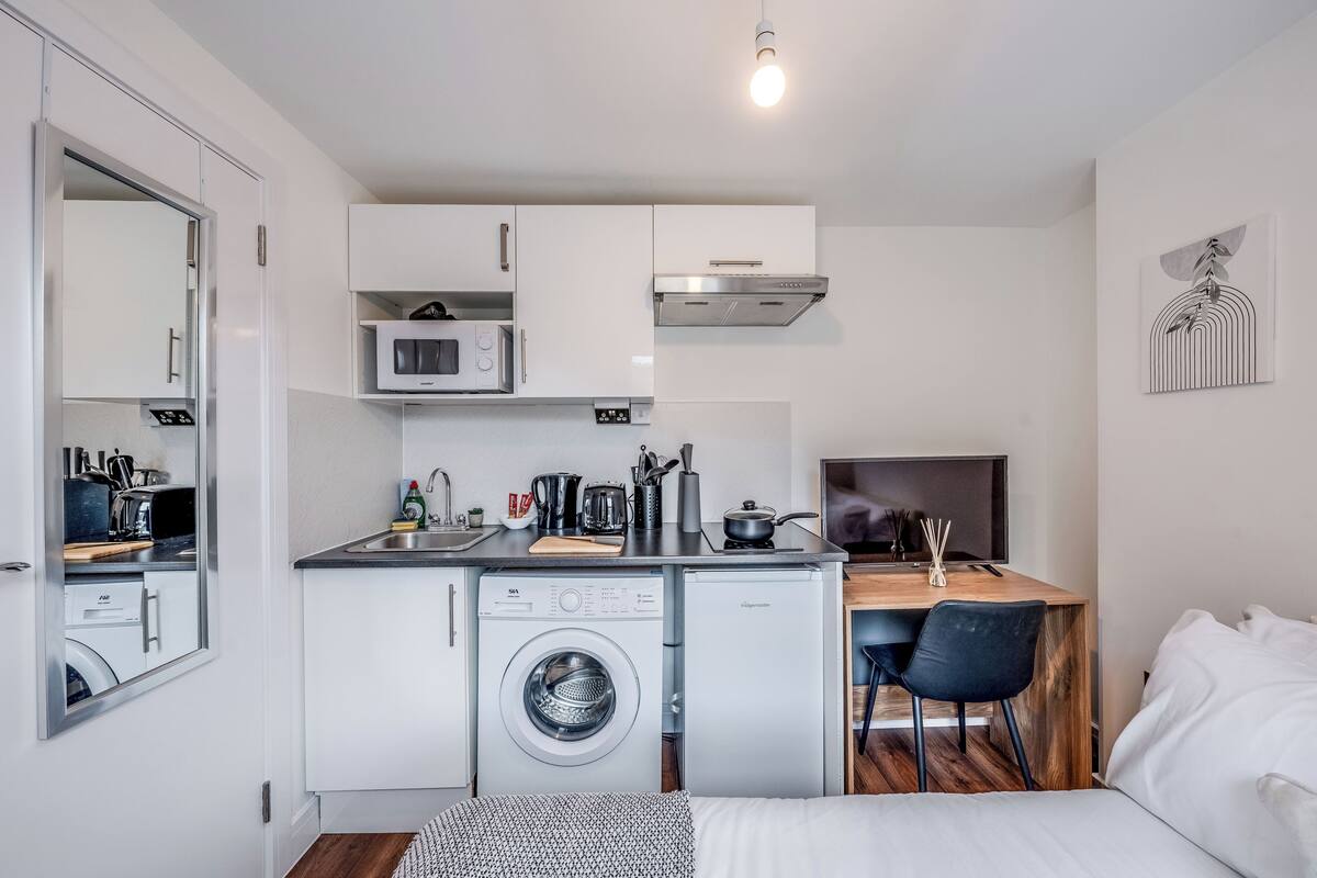 A compact kitchen with a microwave, stove, and washing machine.