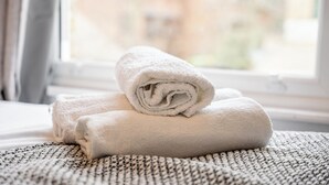 A neatly folded white towel on a textured surface near a window. - Camberwell Studios, 10 mins to Station (London)
