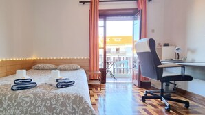 A hotel room with a bed, two towels, a desk with a chair, and a balcony with a chair. - CQ2 | Bedroom w/ Balcony | 3 min walk to HUC - Medicine - Pharmacy | Polo III (Coimbra)