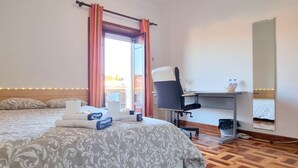 A hotel room with a bed, a desk, a chair, and a window with curtains. - CQ2 | Bedroom w/ Balcony | 3 min walk to HUC - Medicine - Pharmacy | Polo III (Coimbra)