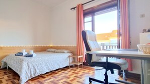 A cozy room with a bed, a chair, a table, and a window with curtains. - CQ2 | Bedroom w/ Balcony | 3 min walk to HUC - Medicine - Pharmacy | Polo III (Coimbra)