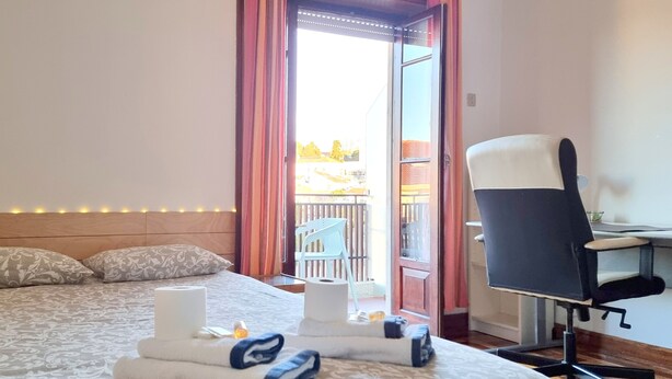 A hotel room with a bed, a desk, a chair, and a balcony with a view. - CQ2 | Bedroom w/ Balcony | 3 min walk to HUC - Medicine - Pharmacy | Polo III (Coimbra)