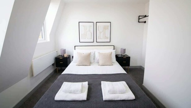 A modern bedroom with a large bed, two bedside tables, and a window. - Stylish 2BR Apartment Near Preston City Centre (Preston)