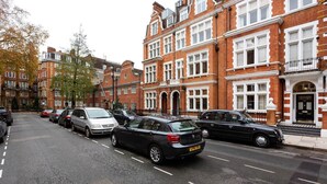 A street lined with red brick houses, parked cars, and trees with autumn leaves. - Gateway to Notting Hill, by Veeve (London)