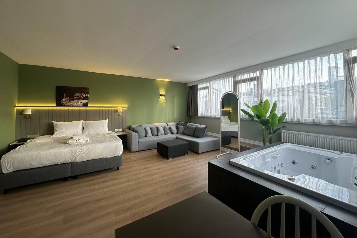 Habitació d'hotel moderna amb llit, sofà i una banyera gran.