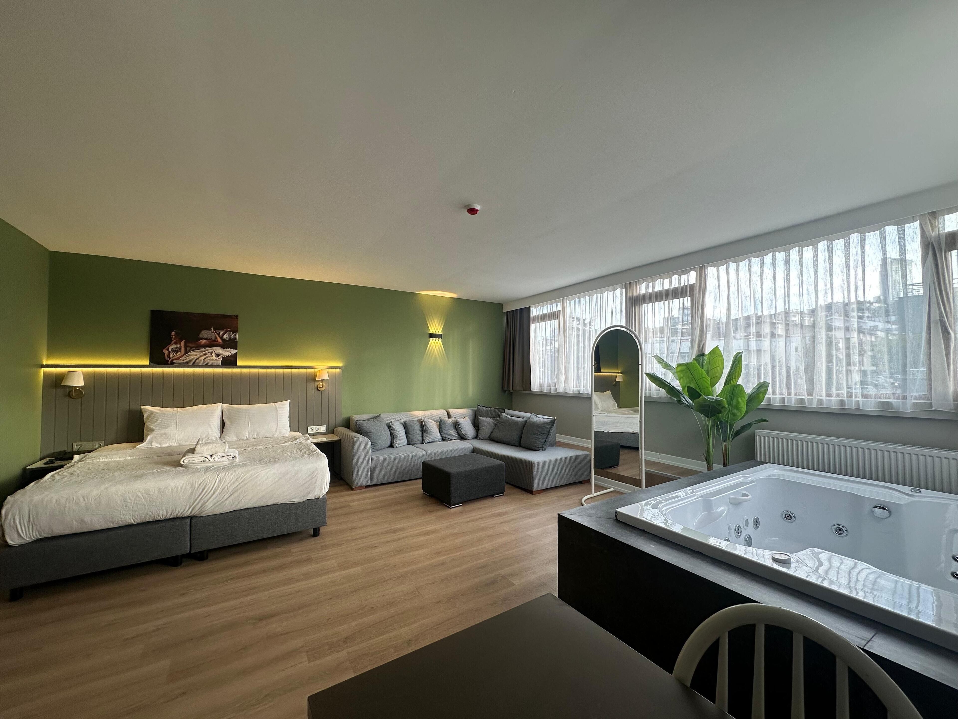 Una habitación de hotel moderna con cama, sofá y jacuzzi.