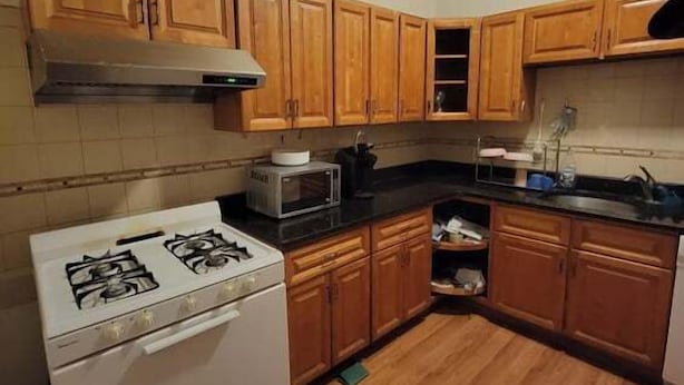 A kitchen with wooden cabinets, a white stove, and a microwave.