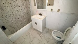 A bathroom with a bathtub, a sink, a toilet, and a mirror.