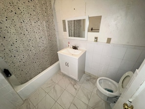 Een bad/douchecombinatie, zeep, toiletpapier