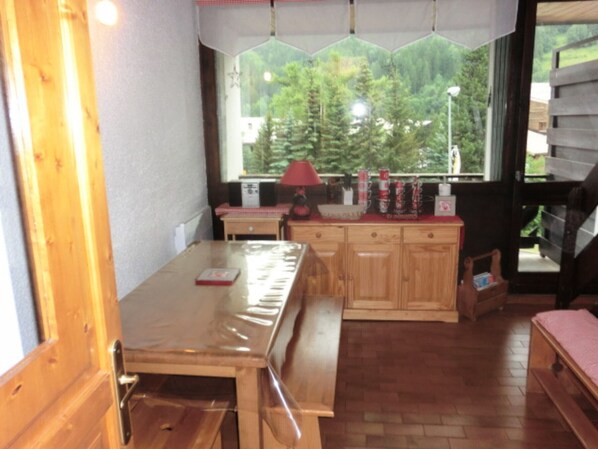 Un intérieur en bois avec un banc, une table et une fenêtre donnant sur les arbres.