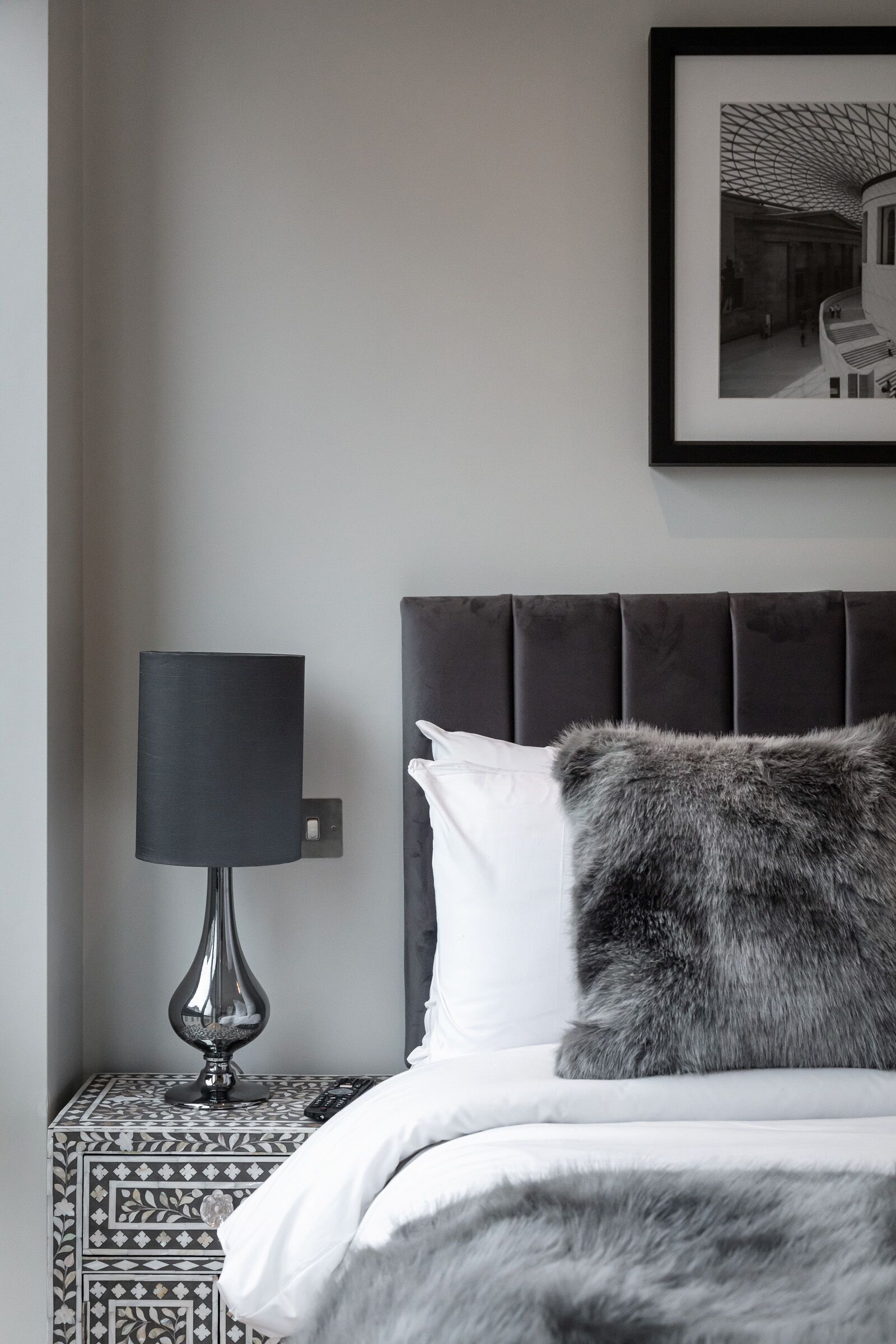 Une chambre à coucher avec un lit, une table de chevet avec une lampe et un tableau encadré au mur.