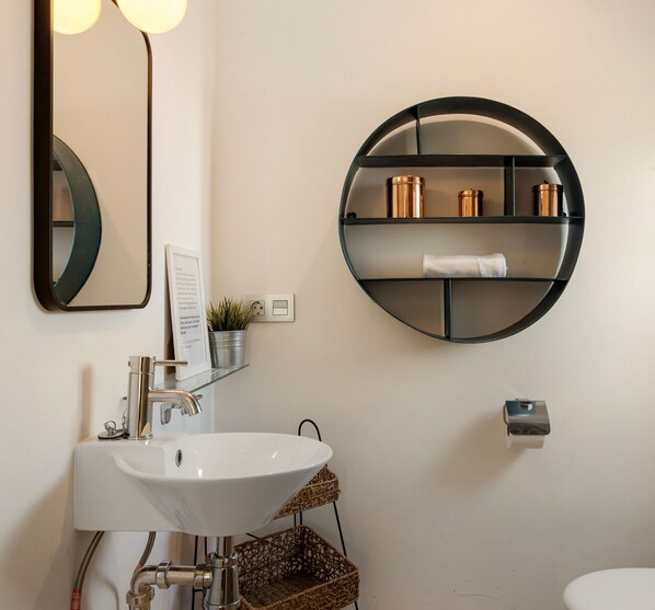 A modern bathroom with a white sink, a round mirror, and a circular shelf with toiletries. - Relaxing Hideaway in Nueva Andaluc a Ref M57 (Marbella)