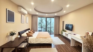 A modern hotel room with a large bed, a desk, a TV, and a balcony with a view.