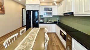 A modern kitchen with white cabinetry, a black refrigerator, and a green tiled backsplash.