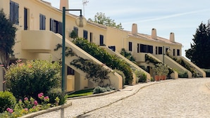 A row of buildings with a cobblestone street, a green lamppost, and a clear sky.
