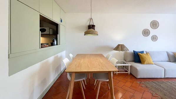 A dining area with a wooden table and chairs, a white sofa, and a hanging lamp.