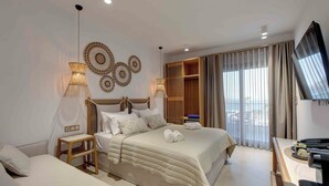 A hotel room with a large bed, bedside tables, a TV, and a view of the outdoors through the window. - Linari Sea & Suites (Ormos Panagias)