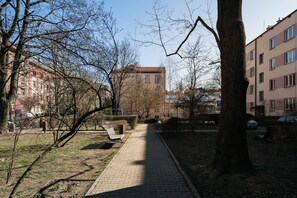 A park pathway with benches, trees, and a building in the background. - Native Apartments Fałata 12 (Kraków)