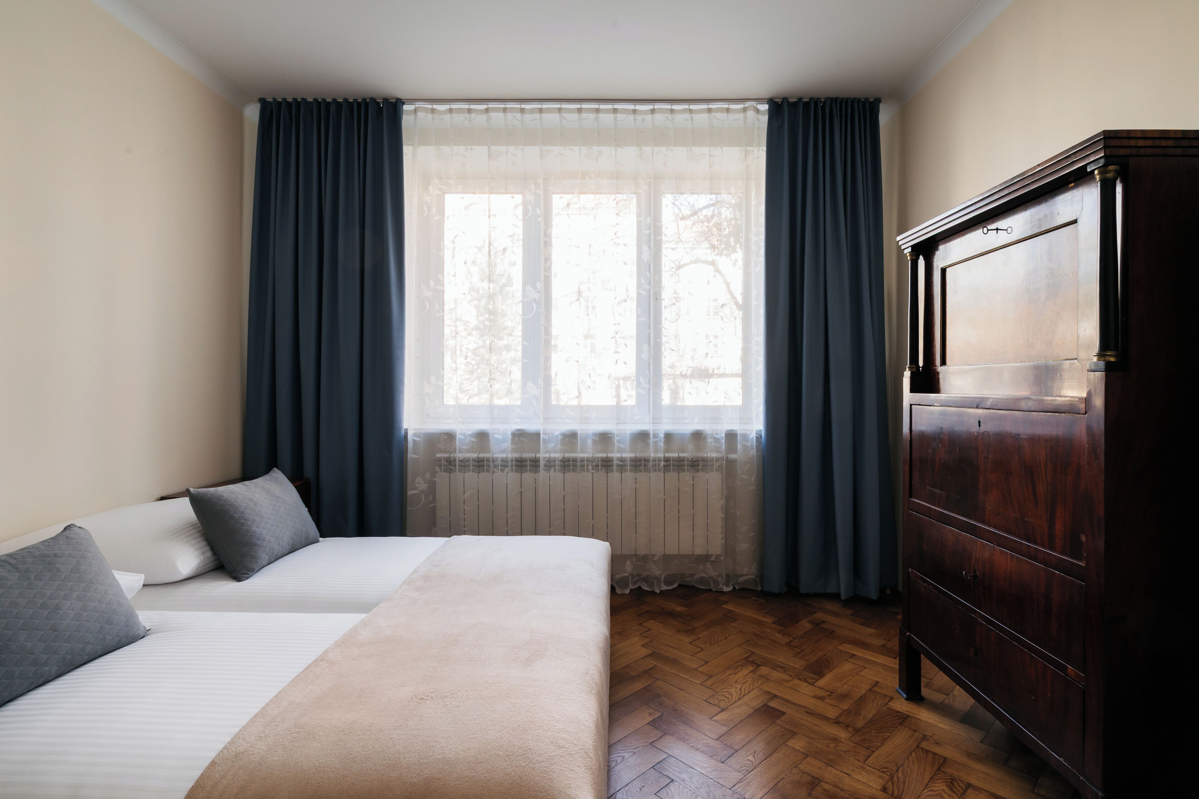 Quarto com cama, cômoda e janela com cortinas.