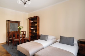 A hotel room with a bed, two bedside tables, a wooden chair, a bookshelf, and a desk with a chair. - Native Apartments Fałata 12 (Kraków)